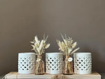 Witte lantaarns met droogbloemen op houten plank
